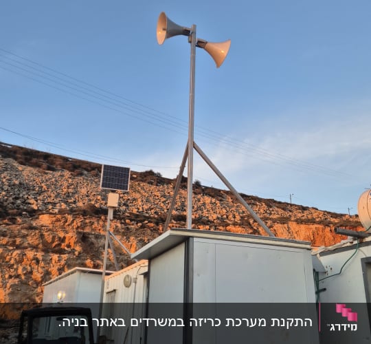 Loudspeakers on a pole with solar panel nearby